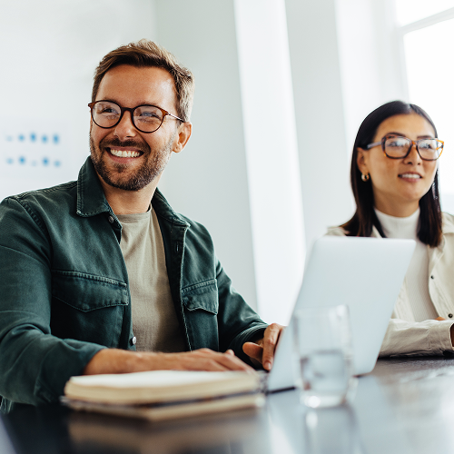 Two colleagues smiling at a meeting.