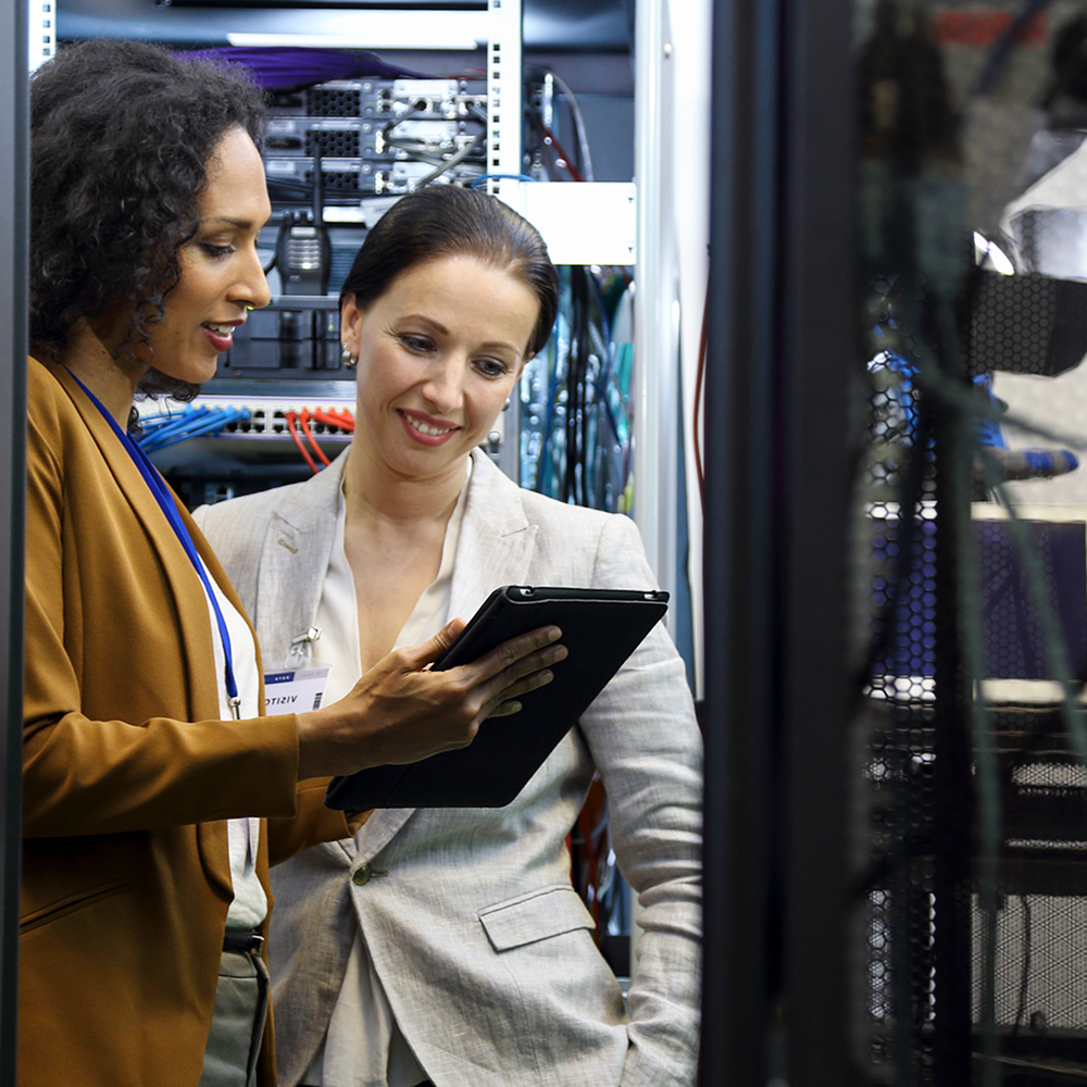 Two female engineers working in the server room.