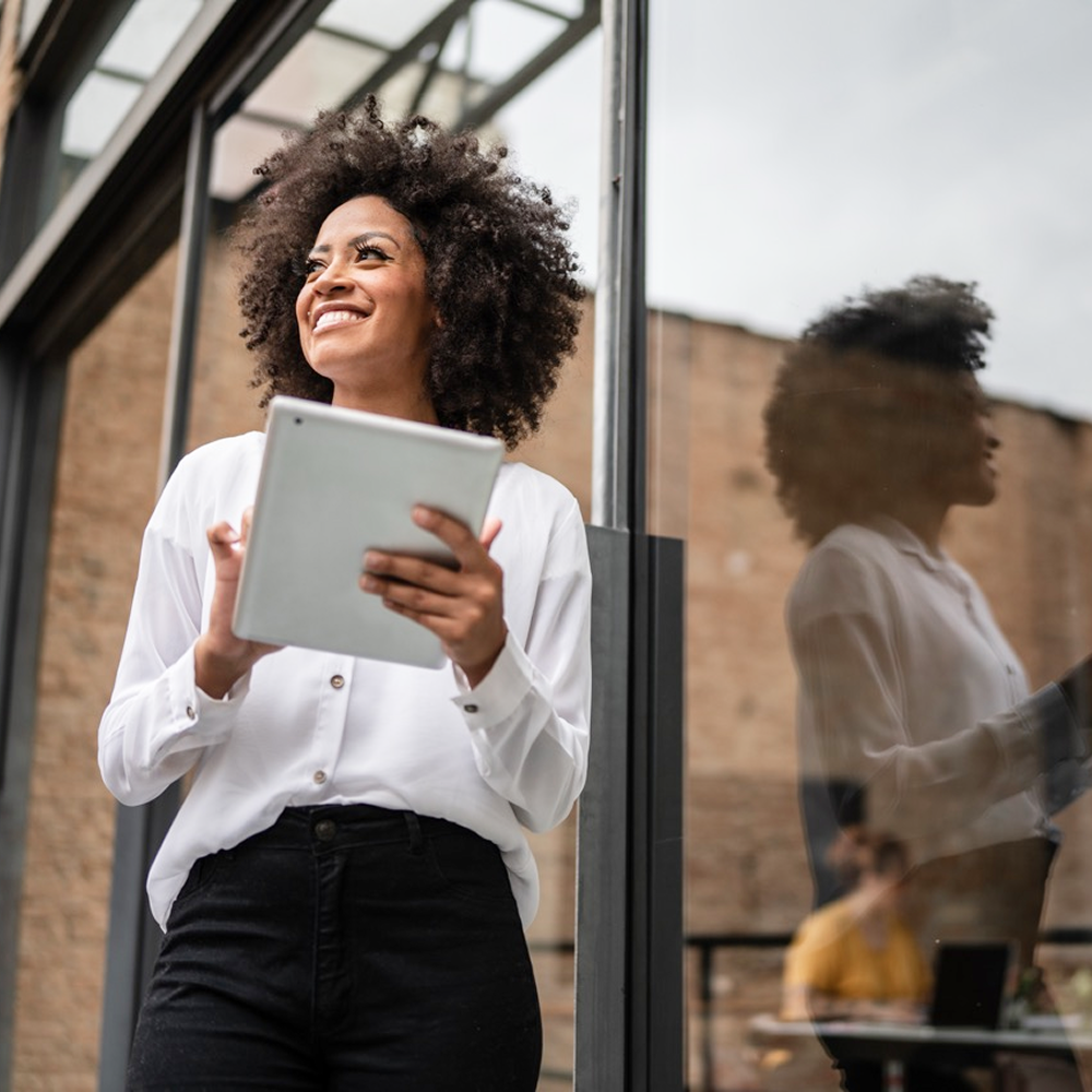 A Black female holding a tablet outside.